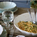SC Hospitality Alentejo white ceramic serving bowl with scalloped edges filled with pasta on a rustic wooden table