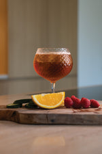 SC Hospitality Mixology balloon goblet with geometric texture filled with a cocktail, garnished with orange and berries