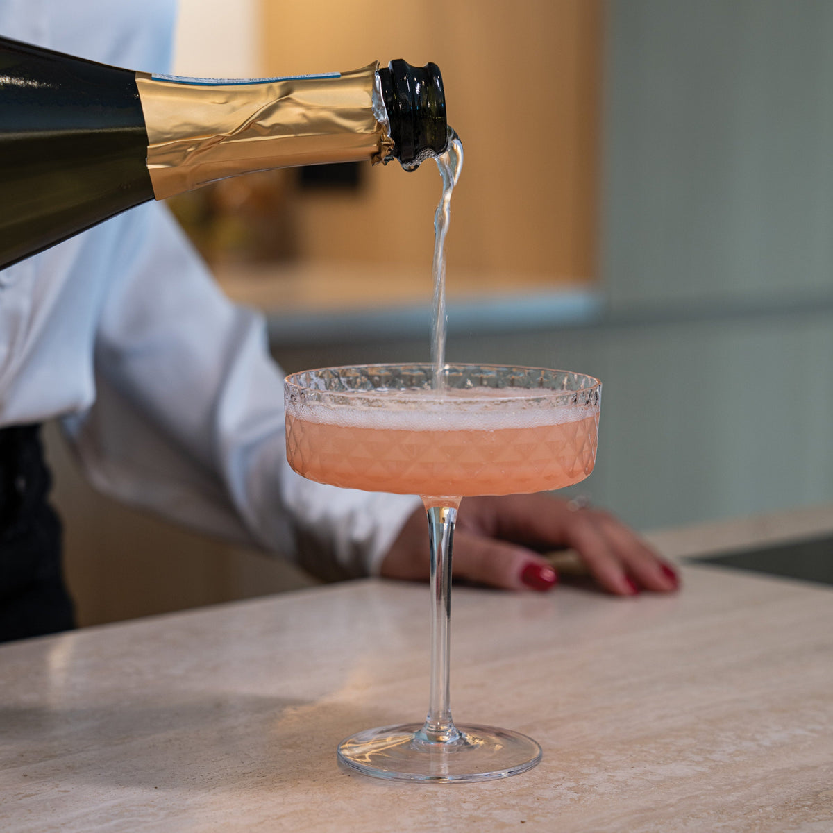 SC Hospitality Zafferano Mixology champagne goblet with geometric texture being filled with sparkling wine