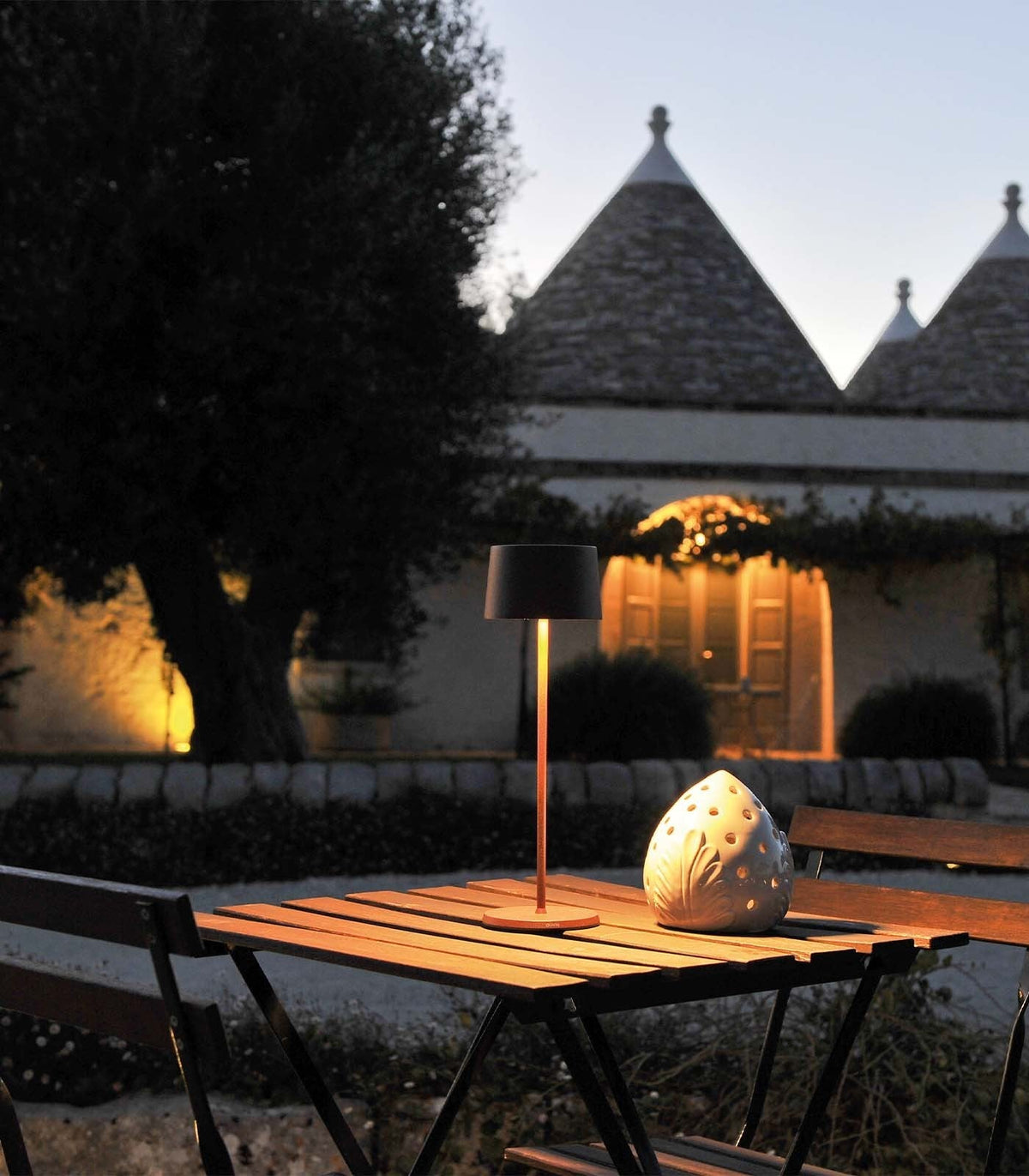 SC Hospitality Olivia Pro cordless table lamp in corten finish on an outdoor terrace at dusk