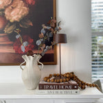 SC Hospitality Olivia Pro cordless table lamp in corten finish, styled on a shelf with books and a decorative vase.