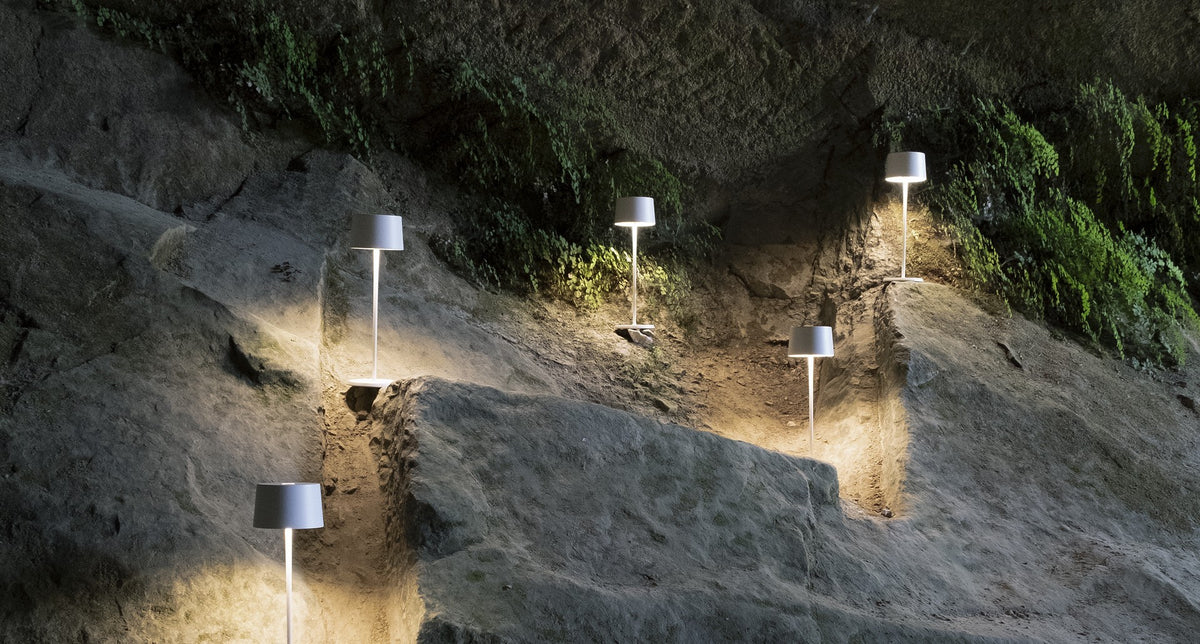 SC Hospitality Olivia Pro white cordless LED table lamps illuminating a rocky outdoor cave wall at night