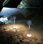 Two white SC Hospitality Olivia Pro cordless LED table lamps illuminating a dark, rocky cave floor.