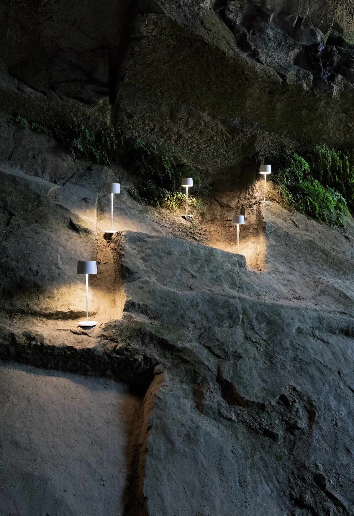 SC Hospitality Olivia Pro white cordless LED table lamps illuminating a rustic stone cave wall