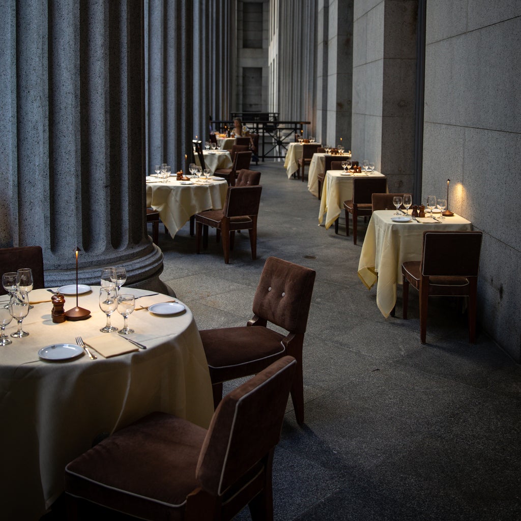 SC Hospitality Pina cordless table lamp in corten finish on a restaurant dining table in a stone colonnade setting