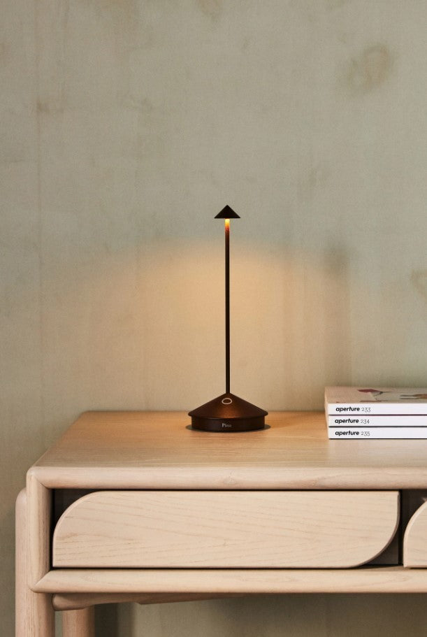 SC Hospitality Pina dark grey cordless rechargeable LED table lamp with a sleek minimalist design on a wooden desk.