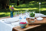 SC Hospitality Pina white cordless rechargeable table lamp on an outdoor dining table with place settings.