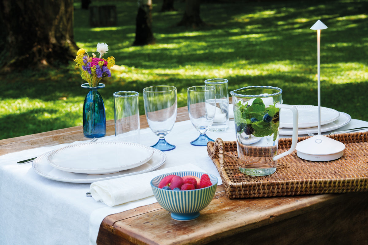 SC Hospitality Pina white cordless rechargeable table lamp on an outdoor dining table with place settings.