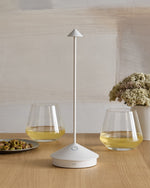 SC Hospitality Pina white cordless rechargeable table lamp with a sleek minimalist design on a wooden dining table.