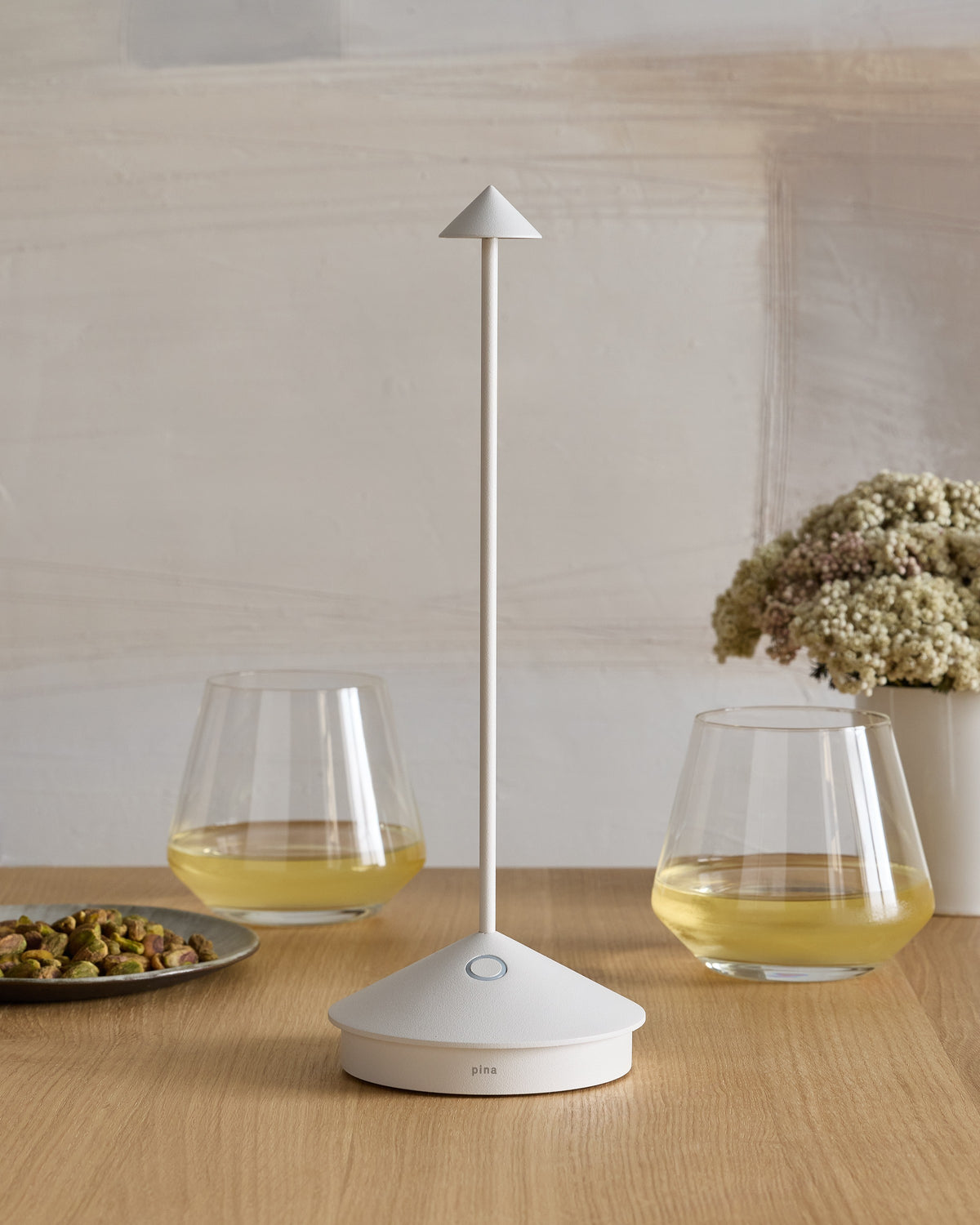 SC Hospitality Pina white cordless rechargeable table lamp with a sleek minimalist design on a wooden dining table.