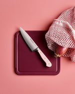 SC Hospitality 16cm cooks knife with a pink Himalayan salt handle and stainless steel blade on a dark red board