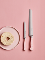SC Hospitality WÜSTHOF bread and utility knives with pink Himalayan salt handles next to a bagel on a pink plate.