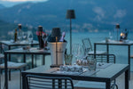 SC Hospitality Poldina Pro dark grey cordless floor lamp on a restaurant terrace overlooking a lake at twilight