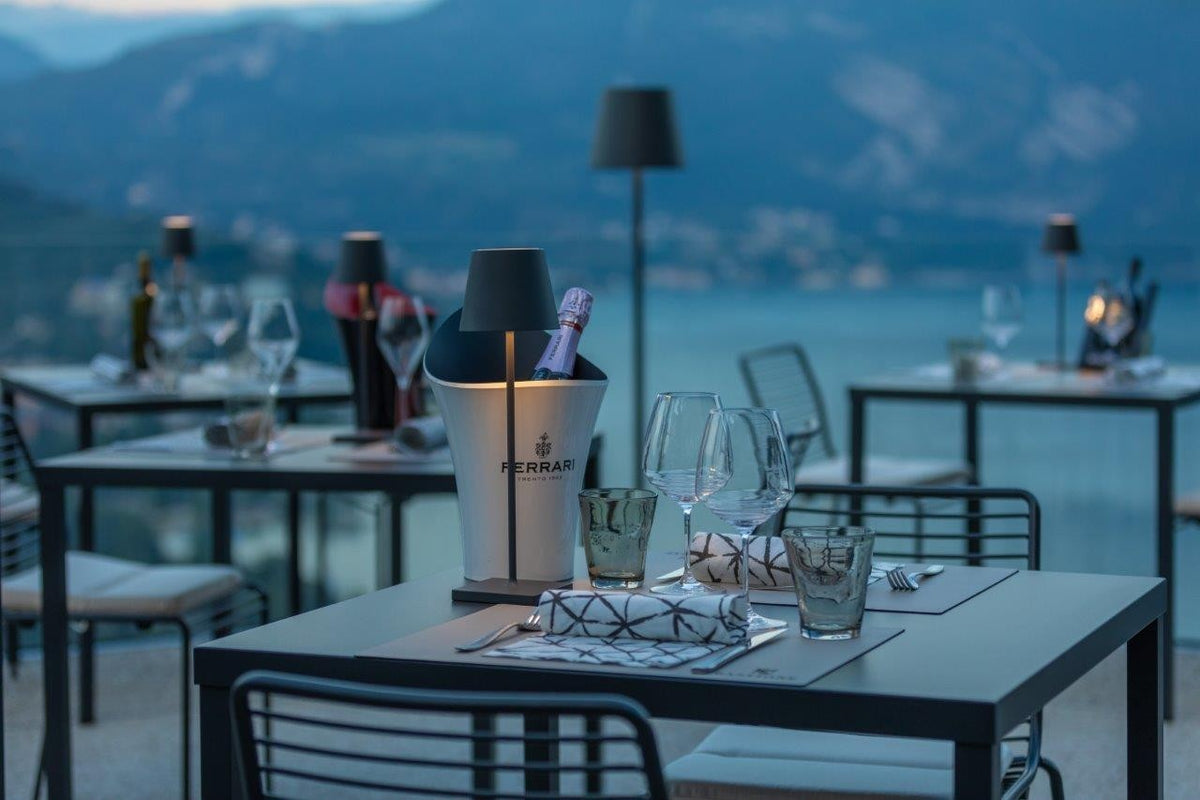 SC Hospitality Poldina Pro dark grey cordless floor lamp on a restaurant terrace overlooking a lake at twilight