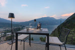SC Hospitality Poldina Pro dark grey cordless floor lamp illuminating an outdoor restaurant terrace at sunset