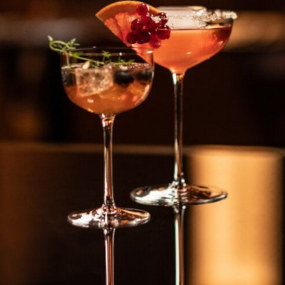 SC Hospitality Tone small cocktail coupe glasses filled with vibrant cocktails, garnished with fruit and herbs.