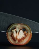 SC Hospitality WÜSTHOF Performer 16cm cooks knife with black DLC coating slicing through a fresh tomato slice