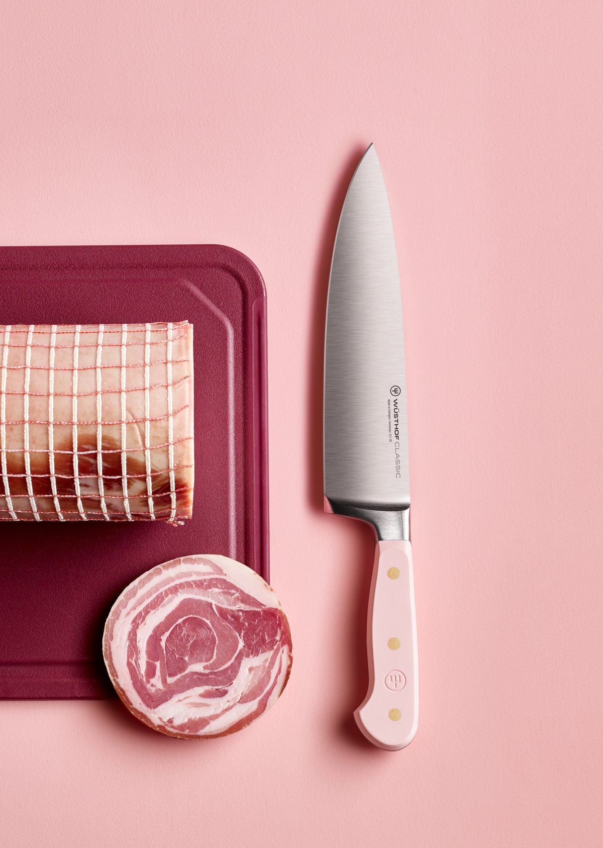 SC Hospitality WÜSTHOF 20cm cooks knife with a pink Himalayan salt handle next to a rolled pork roast on a board