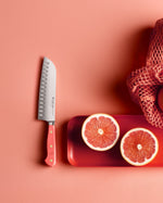 SC Hospitality Wüsthof 17cm Santoku knife with coral peach handle next to sliced grapefruit on a matching tray