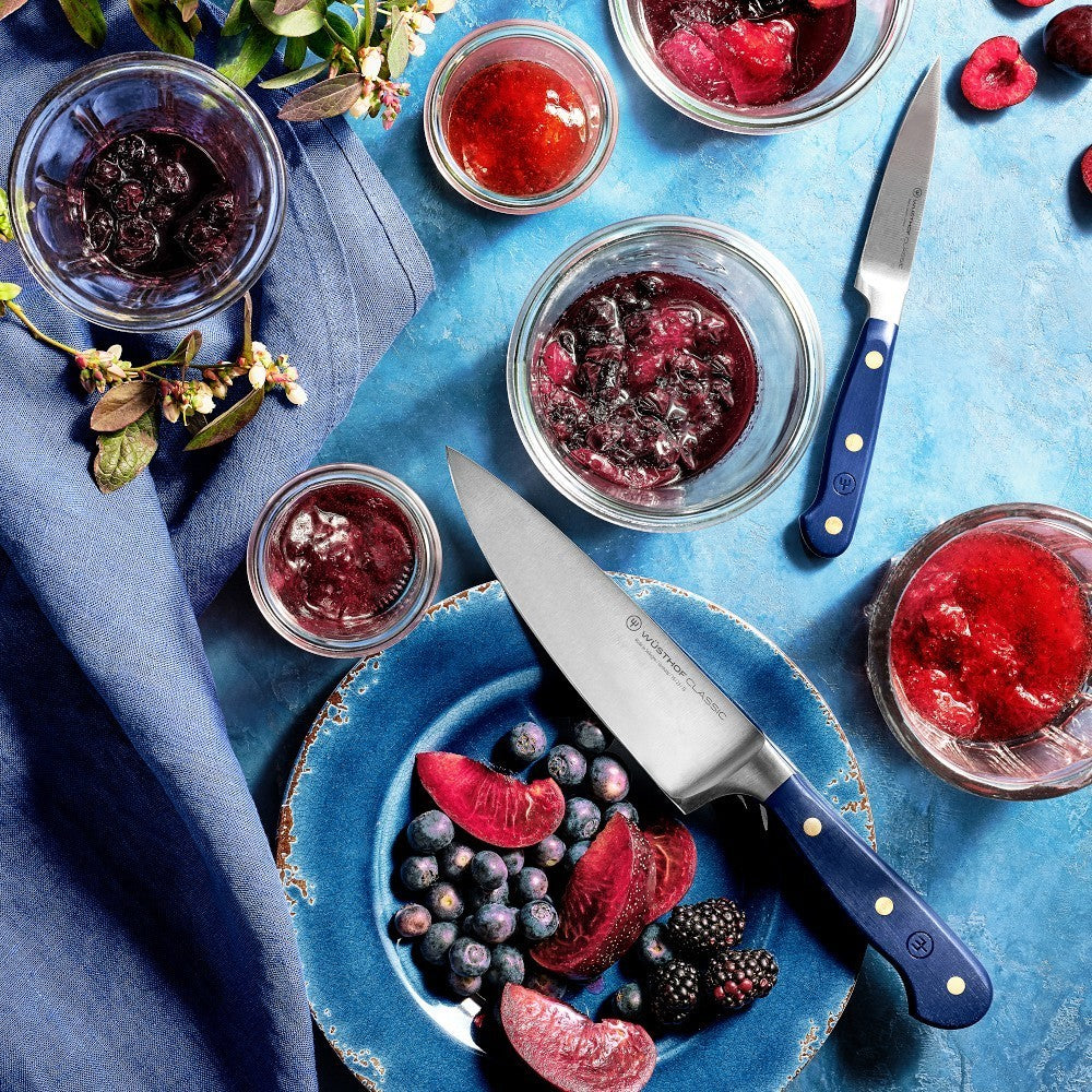 SC Hospitality Wüsthof 20cm cooks knife with wild blueberry synthetic handle resting on a blue plate with berries.
